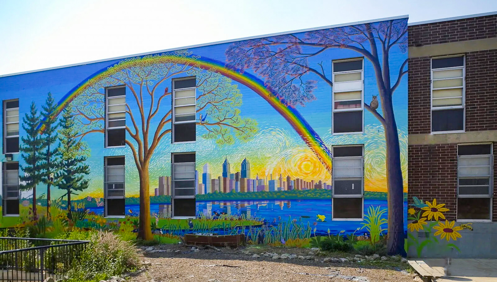 Colorful mural with rainbow, trees, and Philly skyline at Penrose Elementary School